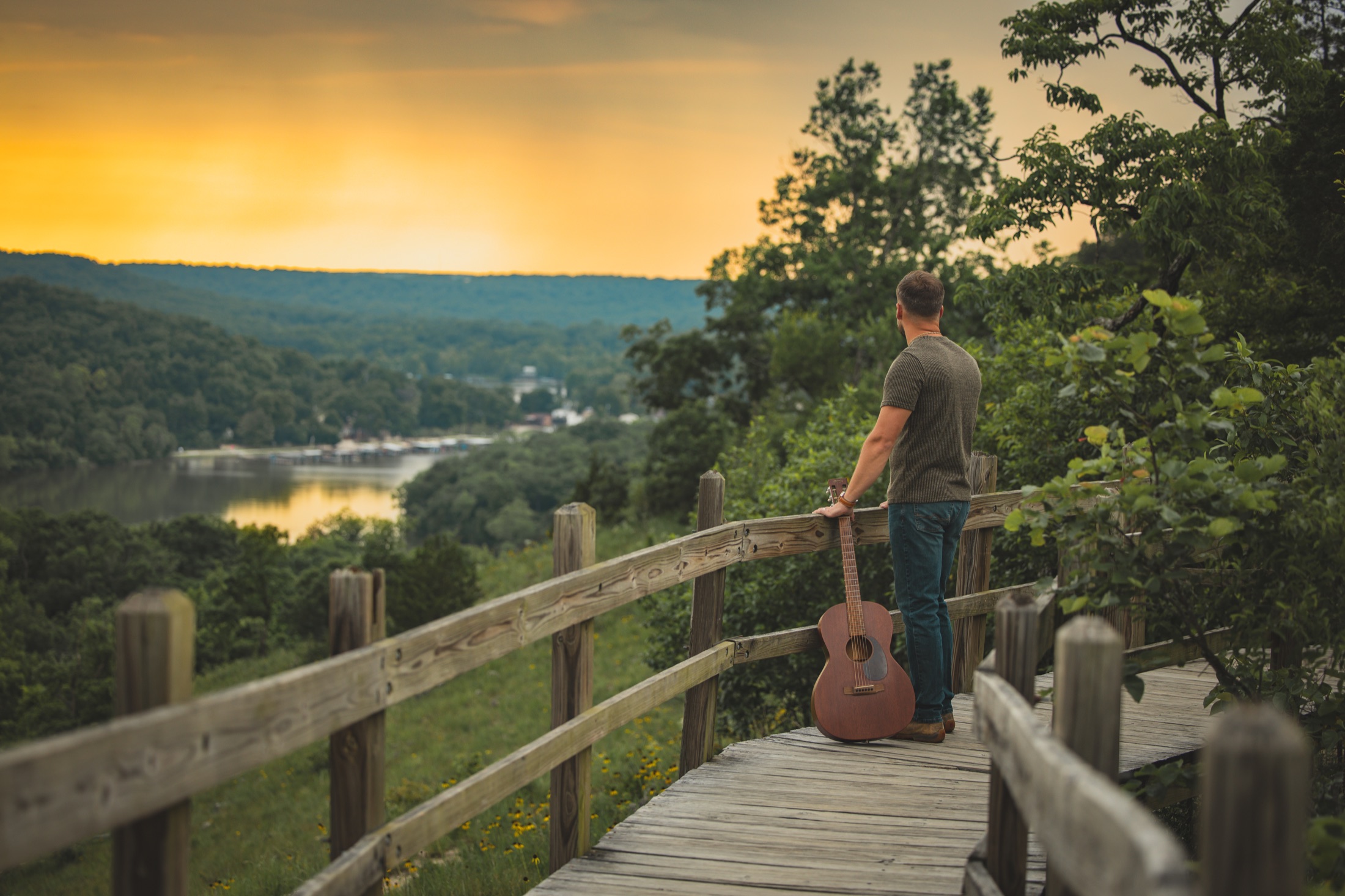Dodge overlooking the lake at sunset with his guitar