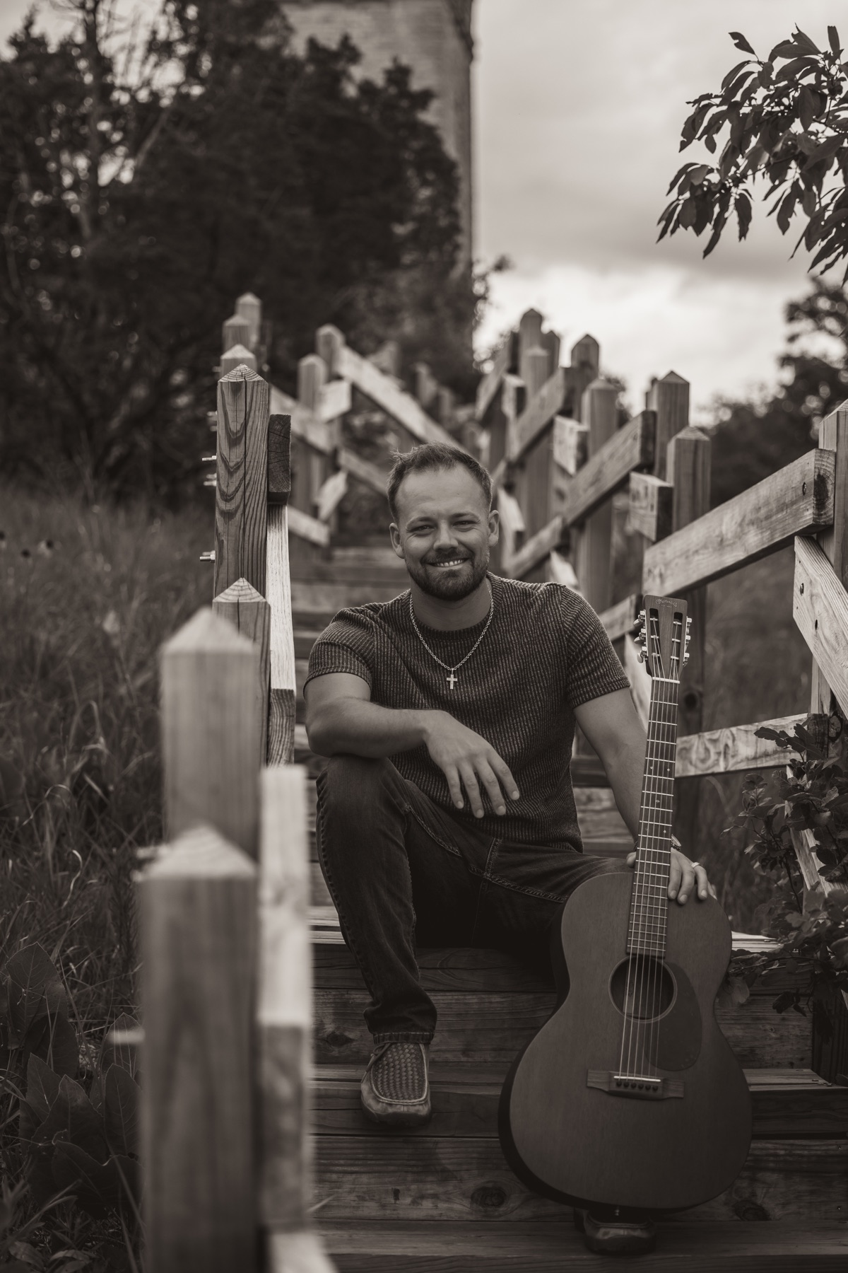 Dodge smiling with his guitar on wooden steps