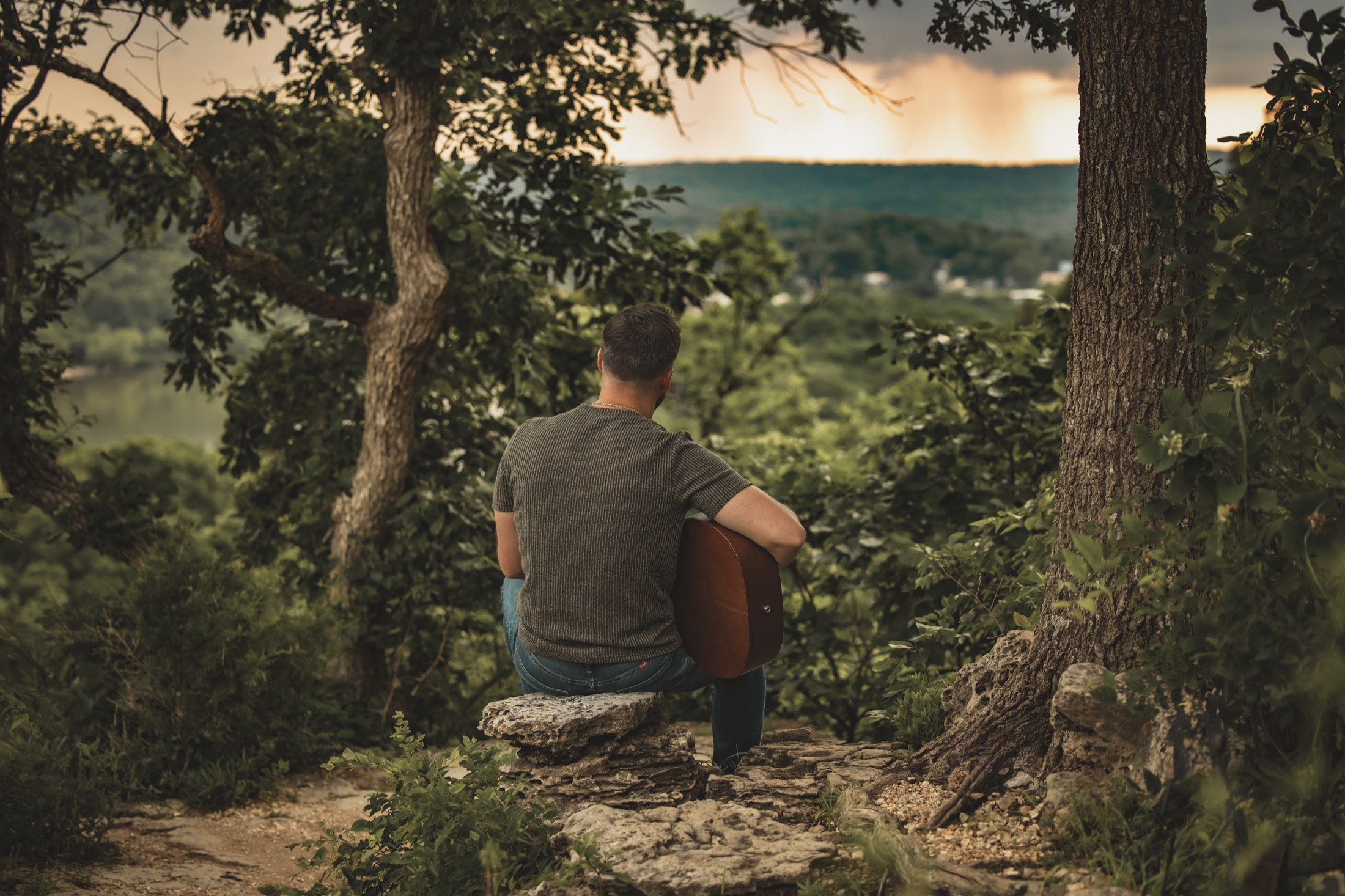 Dodge sitting with his guitar and looking over the Lake of the Ozarks